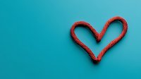 Red rope arranged in heart shape against turquoise background, minimalist composition with copy space for romantic messages and valentines designs.