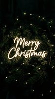 Glowing neon Merry Christmas sign on dark green pine branches with warm fairy lights, festive holiday atmosphere for seasonal cards and decor.