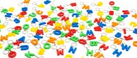 Colorful plastic alphabet letter keychains scattered on white background, bright red, blue, green and yellow ABC charms for kids.