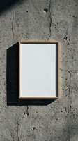 Empty wooden picture frame with white canvas hanging on cracked concrete wall with natural sunlight shadow for mockup and design projects.