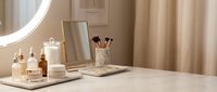 Elegant vanity table with skincare serums, makeup brushes, mirror, and candle in a cozy beige beauty room setup.