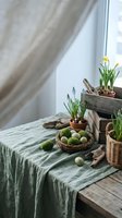 Spring home decor with potted flowers, moss eggs in wicker basket and natural elements on rustic wooden table by window for seasonal interior styling.