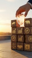 Businessman hand protecting glowing shield over wooden blocks with financial symbols during golden hour sunset representing investment security and risk management.
