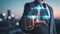 Professional businessman holding glowing digital scales of justice hologram representing legal technology, law firm services, and corporate compliance solutions.