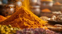Vibrant yellow turmeric powder and aromatic spices with golden particles floating in air, macro food photography showing texture and warm colors in rustic setting.