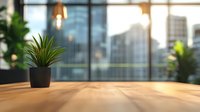 Small potted plant on wooden desk with blurred urban cityscape view through large windows, creating modern office atmosphere with natural elements.