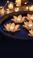 Floating lotus flower candles in blue ceramic bowl with warm fairy lights creating peaceful spa atmosphere for meditation and relaxation rituals.