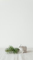 White ceramic elephant figurine next to fresh green pine branch on neutral linen surface. Minimalist holiday and home decor arrangement for seasonal styling and interior design projects.