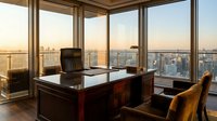 Executive corner office with panoramic city skyline view at sunset, featuring mahogany desk and leather chair for corporate business presentations.