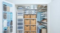 Modern organized walk-in closet with white shelving system, wicker storage baskets, hanging clothes and shoe organizer for home organization solutions.