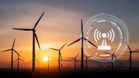 Wind turbines generating renewable energy at sunset with digital wireless connectivity interface overlay for smart grid technology applications.