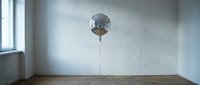 Metallic disco ball suspended from ceiling in empty room with wooden floor and natural light from window.