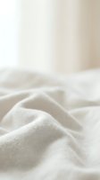 Soft white linen fabric with gentle folds and natural texture, ideal for home decor, bedding, and textile design projects.
