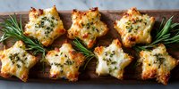 Star-shaped cheese puff pastries with herbs on wooden board, garnished with fresh rosemary sprigs, appetizing golden-brown party food.