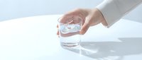 Hand holding a clear glass of fresh water on a white table, soft natural light, minimalist style, clean and pure concept.