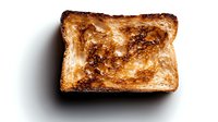 Golden-brown toasted bread slice with crispy surface and charred edges on dark background, isolated food photography for culinary and breakfast concepts.