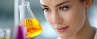 Young female scientist in laboratory looking at yellow liquid in glass flask with purple solution in background, demonstrating research and scientific experimentation.