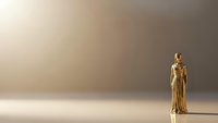 Golden statue of justice figure holding scales on minimalist beige background with dramatic lighting and copy space for legal and law concepts.
