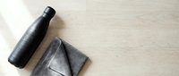 Insulated water bottle and gray folded towel on light wooden surface, flat lay composition for lifestyle and wellness content.