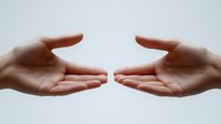 Two open palms reaching toward each other against light background, symbolizing connection, support, partnership and unity in business or personal relationships.