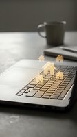 Golden house icons floating above laptop keyboard representing online real estate search and digital property investment opportunities.