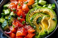 Fresh salmon poke bowl with sliced avocado, cherry tomatoes, cucumber, black sesame seeds and herbs in dark bowl, close up view of healthy food.