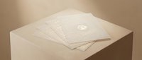 Stacked envelopes with embossed logo on cream pedestal, minimalist business correspondence and corporate branding concept.