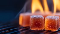 Glowing orange sugar-coated gummy candy cubes on dark background with flames, dramatic lighting creates magical atmosphere for food photography and confectionery marketing.
