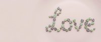 Word love made of small heart shaped stones on pastel pink background, copy space for Valentine's Day greeting card design.