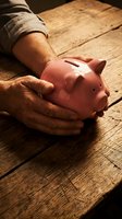 Senior man protecting pink piggy bank with cupped hands on rustic wooden table symbolizing financial security and retirement savings planning.