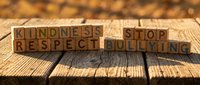 Wooden letter blocks spelling kindness respect stop bullying message on rustic wood surface with warm bokeh background for anti-bullying campaigns.