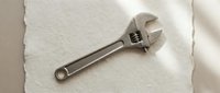 Professional adjustable wrench tool on textured paper background for mechanical work and repair projects in workshop or garage setting.