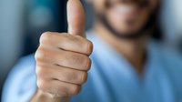 Healthcare worker giving thumbs up gesture showing approval and positive attitude in medical environment for professional communication.