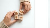 Female hands arranging wooden cubes with eco-friendly symbols on white background. Sustainable lifestyle and environmental awareness concept.