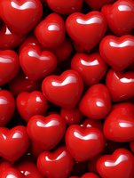 Glossy red heart shapes clustered together creating romantic background for Valentine's Day, love themes, or relationship concepts.