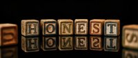 Wooden letter blocks spelling HONEST arranged on dark surface with warm lighting creating professional business concept for trust and integrity themes.