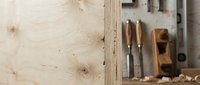 Traditional woodworking tools including chisels and hand plane arranged on natural wood surface with shavings for carpentry and craftsmanship projects.
