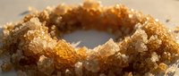 Brown sugar crystals in a ring formation on neutral background, suitable for food, baking, and culinary design projects.