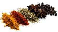 Colorful spices and herbs arranged on white background including turmeric, paprika, oregano, star anise and black peppercorns for culinary cooking.