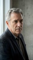 Serious senior Caucasian man with gray hair in dark blazer, thoughtful expression, portrait near window, mature male professional.