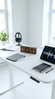 Modern white workspace with headphones, laptop showing audio waveform, wooden NOISE letters, notebook and tablet for sound editing and music production.