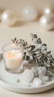 Spa wellness scene with burning candle, eucalyptus branches and white crystals on marble tray creating peaceful meditation atmosphere for relaxation.