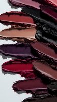 Smeared lipstick swatches in dark burgundy, wine red, black and brown shades on white background, macro shot showing rich texture and pigmentation for cosmetics marketing.
