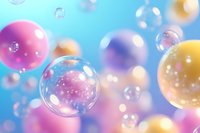 Colorful soap bubbles floating in soft blue atmosphere with pink, purple and yellow spheres creating dreamy bokeh effect and magical sparkles in natural light.