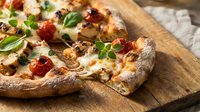 Freshly baked pizza with melted cheese, pepperoni, and basil on wooden board, ready for serving and dining occasions.