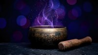 Tibetan singing bowl with wooden mallet releasing mystical purple smoke against starry cosmic background with bokeh lights for meditation and sound healing.