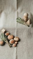 Wooden pumpkin toys and sage bundles arranged on natural linen fabric for autumn crafts and seasonal home decor styling.