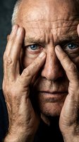 Elderly Caucasian man with blue eyes holding head in hands showing stress, depression, headache or mental health struggles in dramatic portrait.