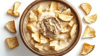 Creamy mushroom soup garnished with crispy croutons in rustic ceramic bowl, overhead view. Rich and hearty homestyle dish with golden bread pieces arranged.