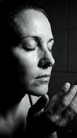 Middle-aged woman with closed eyes and serene expression, hand raised near face in contemplative gesture, monochrome portrait for wellness and mindfulness concepts.